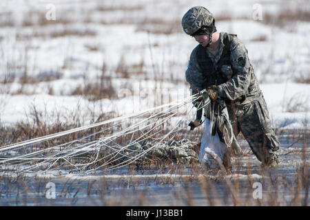 PFC Samuel Kilgore, 1. Bataillon, 501st Fallschirm-Infanterie-Regiment, 4th Infantry Brigade Combat Team (Airborne), 25. Infanterie-Division, U.S. Army Alaska zugewiesen gewinnt seinen Fallschirm während der Durchführung Luftlandeausbildung an gemeinsame Basis Elmendorf-Richardson, Alaska, 13. April 2017. Die Soldaten des 4/25 gehören zu der einzige amerikanische airborne Brigade im Pazifik und sind darauf trainiert, in der Luft Manöver in extrem kalten Wetter/Höhen Umgebungen zur Unterstützung der Kampf, Partnerschaft und Disaster Relief-Operationen ausführen. (U.S. Air Force Photo von Alejandro Pena) Stockfoto