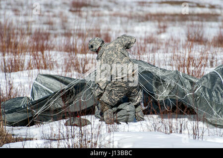 Ein Fallschirmjäger zugewiesen 501st Fallschirm-Infanterie-Regiment, 4th Infantry Brigade Combat Team (Airborne), 1. Bataillon, 25. Infanterie-Division, U.S. Army Alaska, gewinnt seinen Fallschirm während der Durchführung Luftlandeausbildung an gemeinsame Basis Elmendorf-Richardson, Alaska, 13. April 2017. Die Soldaten des 4/25 gehören zu der einzige amerikanische airborne Brigade im Pazifik und sind darauf trainiert, in der Luft Manöver in extrem kalten Wetter/Höhen Umgebungen zur Unterstützung der Kampf, Partnerschaft und Disaster Relief-Operationen ausführen. (U.S. Air Force Photo von Alejandro Pena) Stockfoto