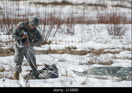 Ein Fallschirmjäger zugewiesen 501st Fallschirm-Infanterie-Regiment, 4th Infantry Brigade Combat Team (Airborne), 1. Bataillon, 25. Infanterie-Division, U.S. Army Alaska, gewinnt seinen Fallschirm während der Durchführung Luftlandeausbildung an gemeinsame Basis Elmendorf-Richardson, Alaska, 13. April 2017. Die Soldaten des 4/25 gehören zu der einzige amerikanische airborne Brigade im Pazifik und sind darauf trainiert, in der Luft Manöver in extrem kalten Wetter/Höhen Umgebungen zur Unterstützung der Kampf, Partnerschaft und Disaster Relief-Operationen ausführen. (U.S. Air Force Photo von Alejandro Pena) Stockfoto