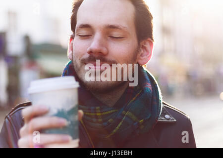 Scarfed Mann warmen Getränk an einem sonnigen Wintertag Stockfoto