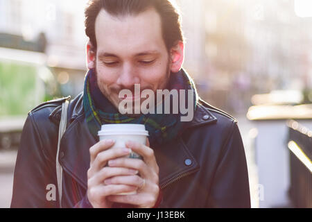 Scarfed Mann warmen Getränk an einem sonnigen Wintertag Stockfoto