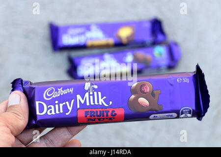 Hand hält Australien Cadbury Frucht und Nuss Schokolade Bar gegen Kuhmilch Hintergrund isoliert Stockfoto