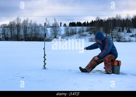 älterer Mann Angeln im Winter auf dem See Stockfoto