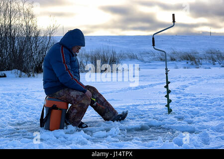 älterer Mann Angeln im Winter auf dem See Stockfoto