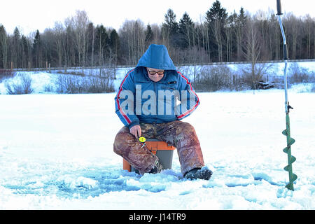 älterer Mann Angeln im Winter auf dem See Stockfoto