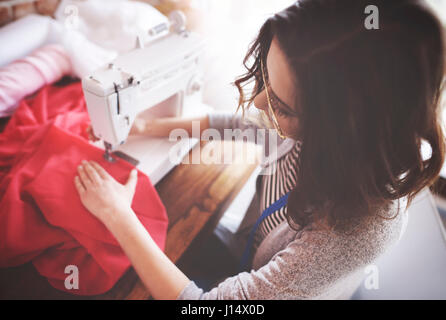 Junge Handwerkerin mit Nähmaschine Stockfoto