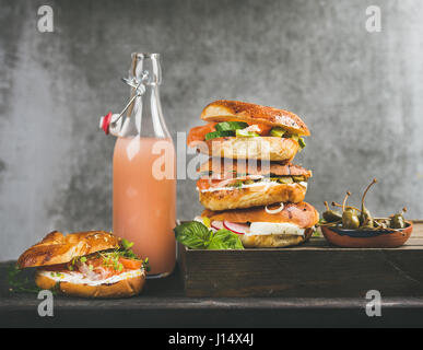 Bagels mit Lachs, Eiern, Gemüse, Kapern und Frischkäse und Grapefruit-Limonade, Flasche grau konkreten Hintergrund. Gesundes Frühstück, Mittagessen oder Stockfoto