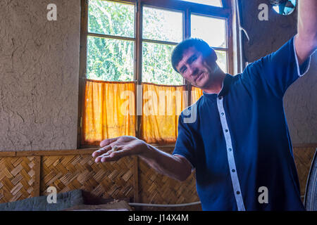 MARGILAN, Usbekistan - 20 AUGUST: Mann zeigt Seidenfaden aus einem Kokon Seidenraupe in eine Seidenfabrik. August 2016 Stockfoto