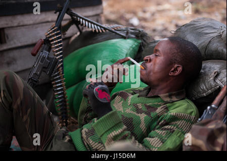 Soldat der Demokratischen Republik Kongo hat eine Zigarettenpause an der Front während der Operationen gegen die ruandischen gestützte Miliz M23 Stockfoto