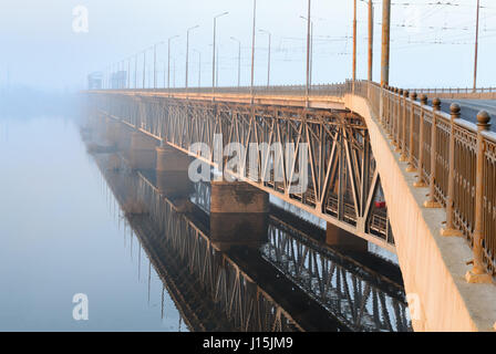 Eisenbahnbrücke in einem nebligen Morgen in den Strahlen der aufgehenden Sonne. Dnepropetrovsk, Ukraine Stockfoto