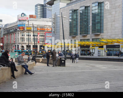 Exchange Square im Zentrum von Manchester, England, Menschen sitzen, warten und entspannen mit der bunten bunte Tram-Station in der b/g zu zeigen. Stockfoto