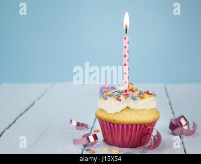 Cup Cake mit einer Kerze auf blauem Hintergrund Stockfoto