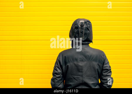 Probleme und Hindernisse im Leben, Frau in Kapuzen Winterjacke vor der Wand eine Herausforderung Stockfoto