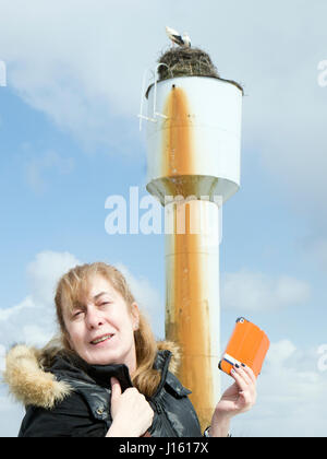 Frau etwa, einen guten Schuss auf ihr Handy von einem Storchennest, Outdoor-beschnitten-Porträt Stockfoto