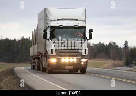 SALO, Finnland - 24. März 2016: Weiß Scania Lkw und Kombination Trailer bewegt sich entlang der Autobahn im Süden von Finnland. Der Fahrer blinkt die Fernlicht-l Stockfoto