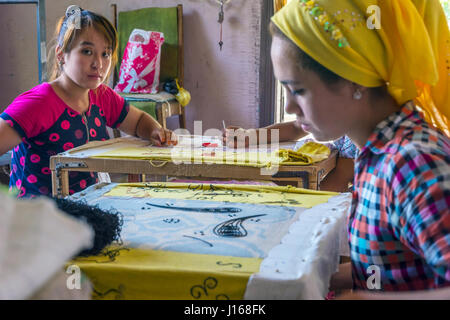 MARGILAN, Usbekistan - 20 AUGUST: Frau Sticken Stoff von hand mit traditionellen usbekischen Mustern in eine Seidenfabrik Werkstatt. August 2016 Stockfoto