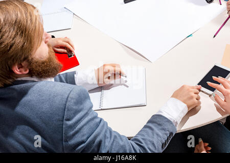 Der Mann sitzt hinter der Rezeption, Überprüfung Berichte, reden. Stockfoto