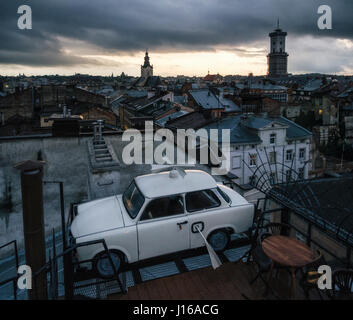 Lviv, Ukraine - 22. September 2016: Trabant Auto geparkt auf dem Dach ein historisches Gebäudes Haus der Legenden in der Dämmerung. Wahrzeichen von Lemberg, Ukraine. Stockfoto