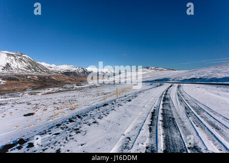 Spuren im Schnee bedeckt Bergstraße vor den Toren Ólafsvik, Halbinsel Snæfellsnes (Snaefellsnes), West-Island Stockfoto