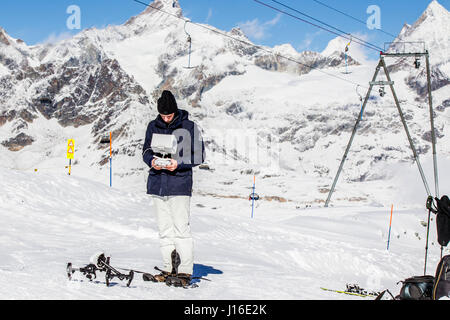 Drohne-Betreiber stehen auf Schnee unter Skilift in Bergen Stockfoto