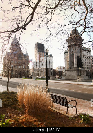 Syracuse, New York, USA. 16. April 2017. Blick auf eine Bank und Street Lampe in Clinton Square mit den Soldaten und Matrosen-Denkmal, Syrakus Einsparungen Stockfoto