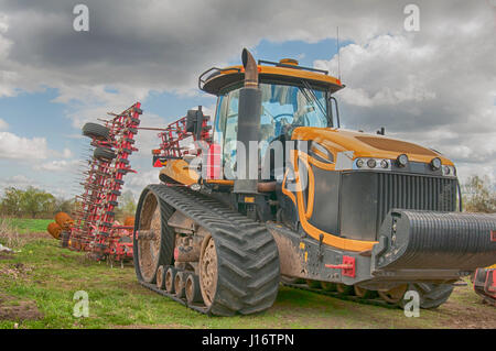 ein große gelbe Traktor verarbeitet das Feld Stockfoto