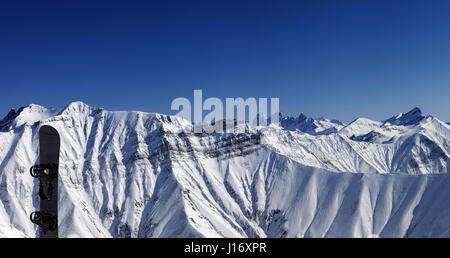 Panoramablick auf schneebedeckte Berge und Snowboard im schönen Tag Stockfoto