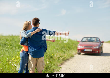 paar Trampen und Anhalten von Autos auf Land Stockfoto