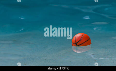 Spielzeug-Basketball ist in einem Pool schwimmen. Stockfoto
