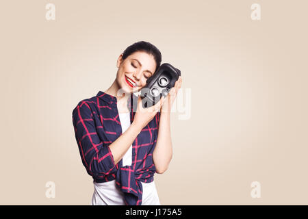 Junge schöne Frau im lässigen Stil mit virtual-Reality-Kopfhörer auf beigen Hintergrund. Studio gedreht. Stockfoto