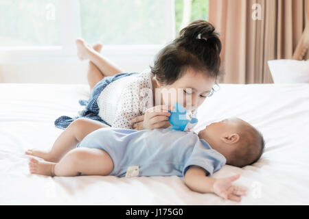 Asiatisches Baby Bruder und Kleinkind Schwester Drill Puppe im Schlafzimmer. Glückliche Familie. Stockfoto