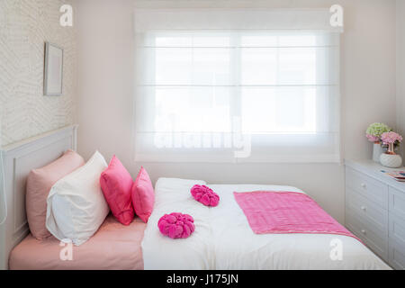 Innere des weißen Schlafzimmer mit Doppelbett und rosa Kissen und Bücherregal zu Hause. Stockfoto