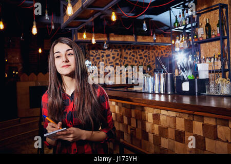 Ein Kellner Arbeitermädchen nimmt eine Bestellung im Cafébar Stockfoto