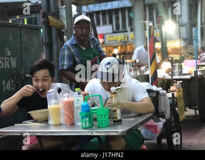 Bangkok, Thailand. 19. April 2017. Zwei Männer Essen in ein open-air-Restaurant in Bangkok, Thailand, 19. April 2017. Die Stadt ist stolz auf seine kulinarische Vielfalt welche inbegriffen rund eine halbe million solche Küchen. Die städtischen Behörden haben angekündigt, dass sie planen, die Küchen in der Nähe. Protest ist bereits Montage. Foto: Christoph Sator, Dpa/Alamy Live News Stockfoto