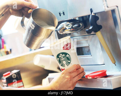 ILLUSTRATION - ein Starbucks Arbeiter gießt einen Kaffee in einem wiederverwendbaren Pappbecher in Duisburg, Deutschland, 19. April 2017. Kunden können 30 Cent auf ihre heiße Getränke sparen, wenn sie ihre eigenen Tassen bringen. Foto: Roland Weihrauch/dpa Stockfoto