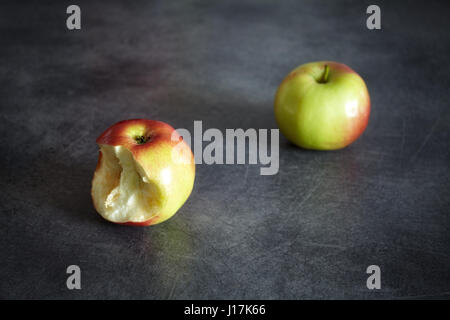 Zwei reife Äpfel, eine gebissen und einem ganzen auf einem dunklen Hintergrund, Tiefenschärfe, Platz für Text. Stockfoto