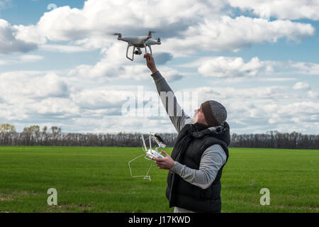 Mann, Abhaltung von fliegenden Drohne Quadrocopter auf der grünen Wiese. Stockfoto