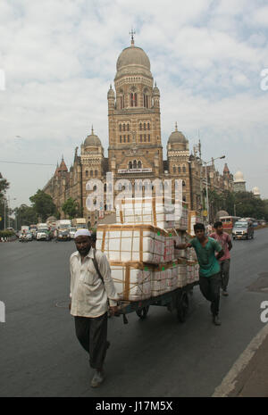 Männer ziehen Karren, beladen mit Packungen von Gütern auf der Straße in Mumbai, Indien Stockfoto