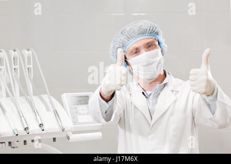 Porträt von glücklichen männlichen Zahnarzt tragen Laborkittel sitzend in Klinik Stockfoto