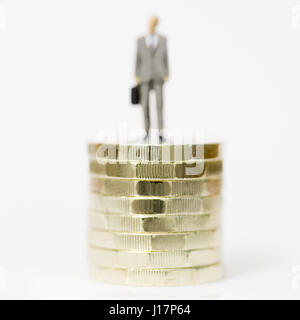 Nahaufnahme / Makro Modell stock Foto Darstellung männlichen Lohn Arbeiter auf Stapel der neuen britischen Pfund Münzen. Stockfoto