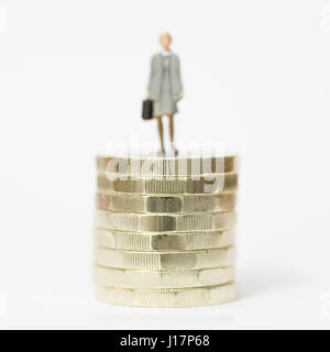 Nahaufnahme / Makro Modell stock Foto Darstellung weiblicher Lohn Arbeiter auf Stapel der neuen britischen Pfund Münzen. Stockfoto