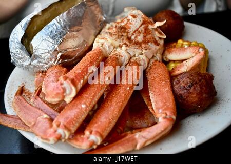 Schnee-Krabbenbeine serviert mit Ofenkartoffel und hushpuppies Stockfoto