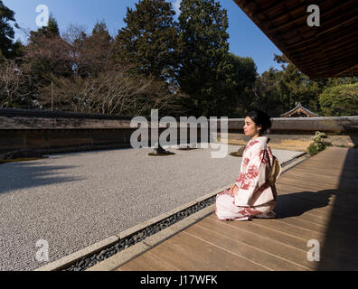 Junge Japanerin Kimono kniet neben den Steingarten an Ryōan-Ji, Kyoto. Eines der schönsten Beispiele für einen Verleih-Niwa Steingarten. Zen meditatio Stockfoto