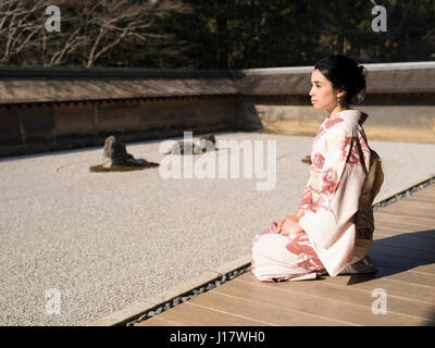 Junge Japanerin Kimono kniet neben den Steingarten an Ryōan-Ji, Kyoto. Eines der schönsten Beispiele für einen Verleih-Niwa Steingarten. Zen meditatio Stockfoto