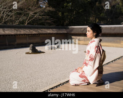 Junge Japanerin Kimono kniet neben den Steingarten an Ryōan-Ji, Kyoto. Eines der schönsten Beispiele für einen Verleih-Niwa Steingarten. Zen meditatio Stockfoto