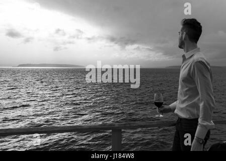 Kontemplative Mann mit Rotwein auf hoher See Stockfoto