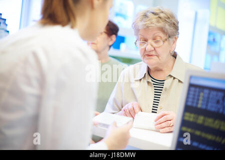 Ältere Kunden an Kasse mit Apotheker Stockfoto