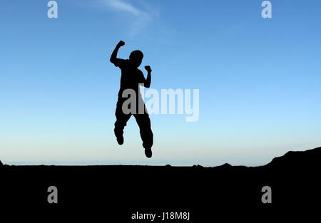 Ein glücklicher Mann springt in die Luft, in der silhouette Stockfoto