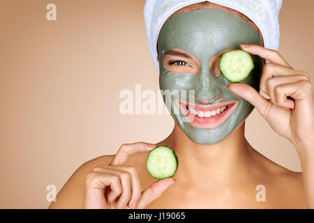 Attraktives Mädchen mit Gurkenscheiben bis zu den Augen. Foto eines Mädchens mit einer Gesichtsmaske. Schönheit & Skin care Konzept Stockfoto