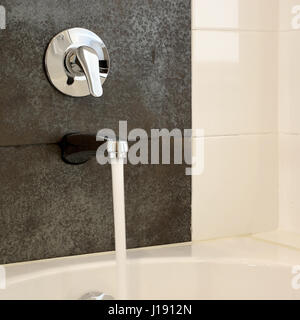 moderne Badewanne mit fließendem Wasser vom Wasserhahn Stockfoto